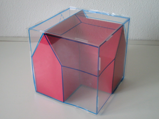 Ein pinkfarbener und blauer Wahlkasten mit offenem Deckel, der seinen Inhalt zeigt, steht auf einem weißen Tisch an einer Wand.