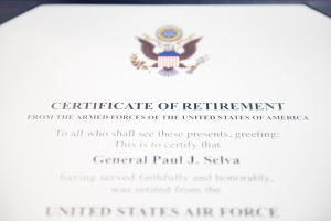 Rahmenurkunde zur Verabschiedung von der United States Air Force mit blauem Rand, schwarzer Schrift und einem zentralen Schild-Logo mit einem Stern, einem Lorbeerkranz und einer 'Verabschiedung'-Banderole.