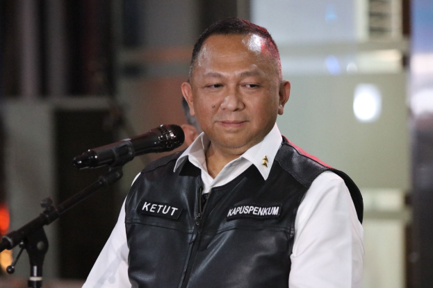 Mann in schwarzer Weste und weißem Hemd vor einem Mikrofon stehend, der besorgt wirkt, mit einem unscharfen Hintergrund.