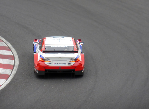 Rotes und weißes Toyota Supra GT3-Sportwagen auf einer Rennstrecke, mit 'Toyota Supra GT3'-Text an der Seite, mittig im Bild.