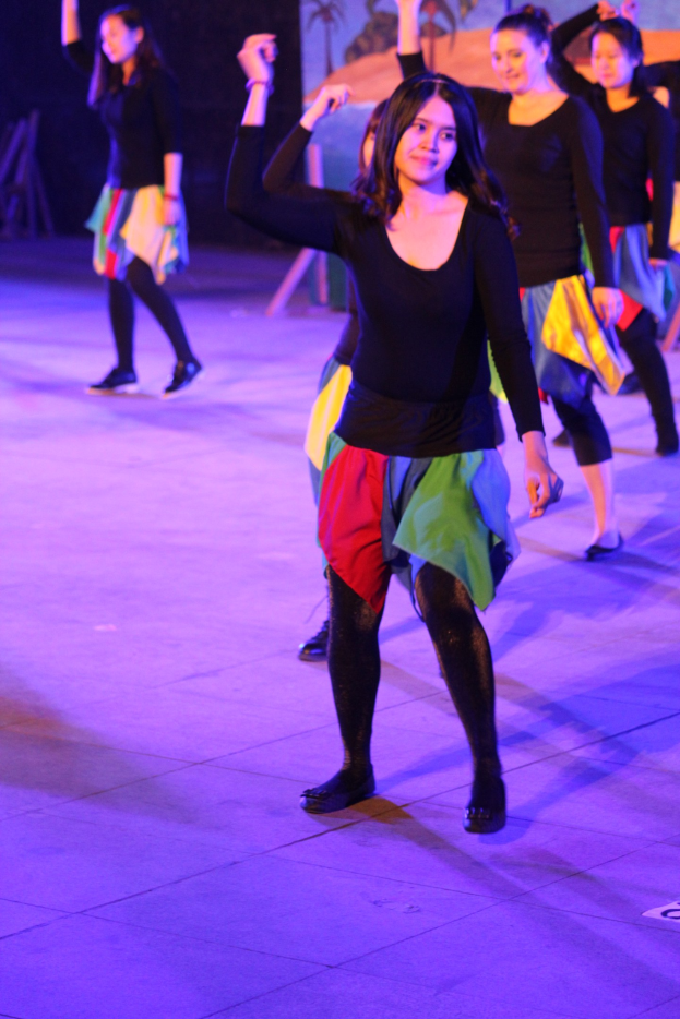 Eine Gruppe junger Frauen, die auf einer Bühne tanzen, mit einem Gemälde im Hintergrund.