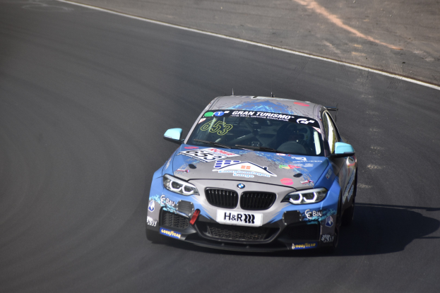 BMW M2 GT3 Rennwagen auf der Rennstrecke mit Text und Zahlen auf der Karosserie.