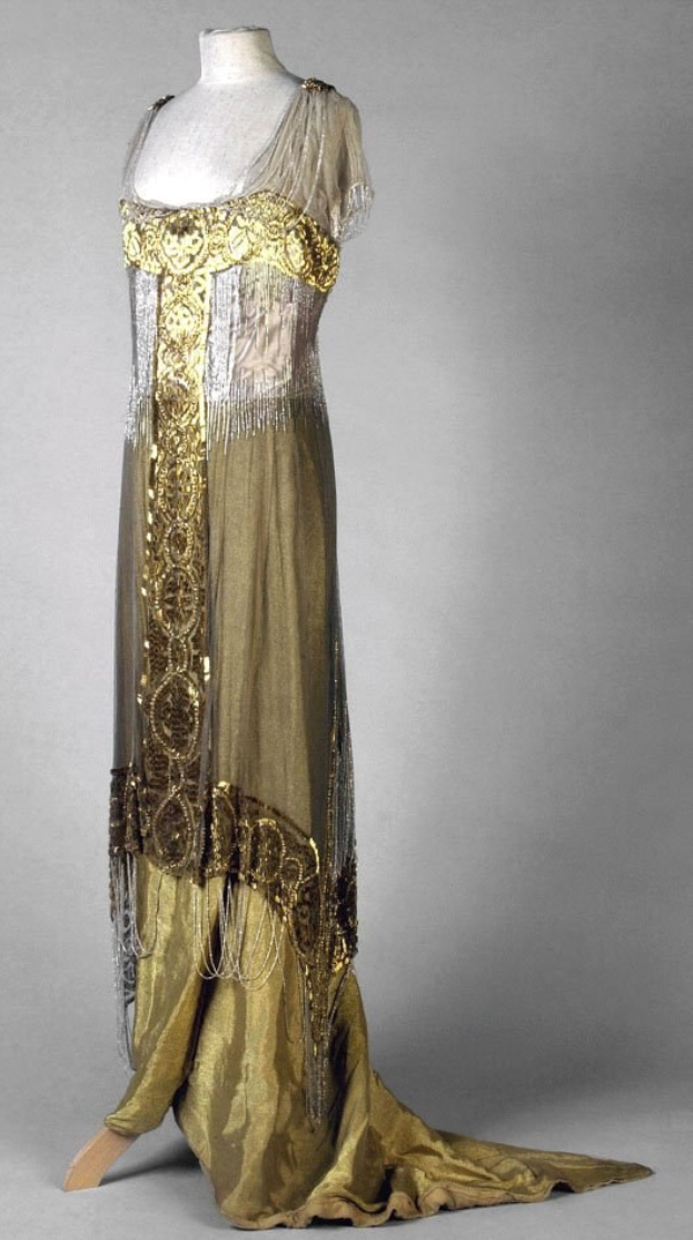 Eine Schaufensterpuppe in einem goldenen und silbernen Abendkleid aus den 1920er Jahren mit aufwendiger Goldstickerei und Perlen