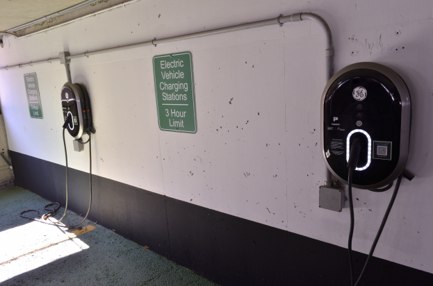 Wandmontierte Ladepunkte für Elektrofahrzeuge in einer Tiefgarage mit Informationsschildern darunter.