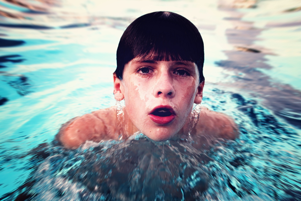 Ein Junge schwimmt in der Mitte eines Gewössers.