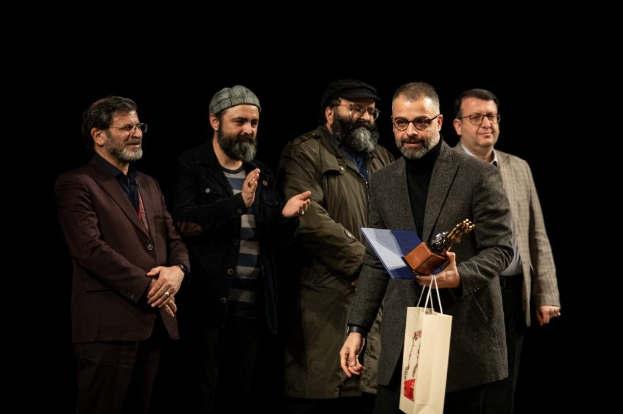 Eine Gruppe von Männern auf einer Bühne mit einer Tasche und einer Trophäe bei der Eröffnungsnacht des Berliner Filmfestivals.