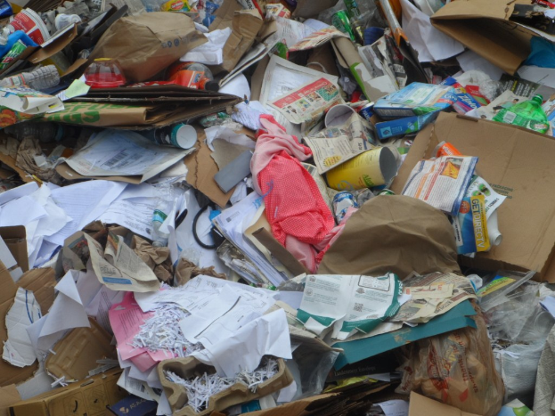 Ein unordentlicher Haufen Kartons mit verschiedenen Gegenständen wie Papieren, Flaschen und Abdeckungen.