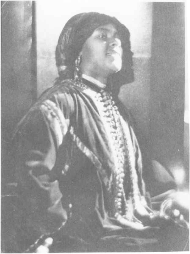 Schwarz-weiß-Foto einer Frau in Kleid und Schmuck vor einer Wand sitzend, mit Text unten, der besagt, dass sie angeblich die erste indische Frau ist, die zum US-Präsidenten gewählt wurde.