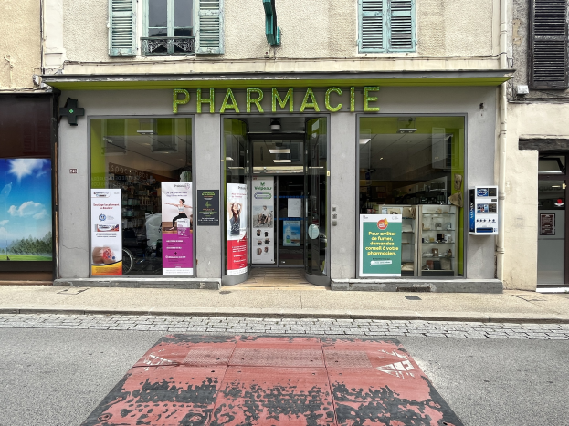 Apotheke mit Glaswänden und -türen, Plakate an den Innenwänden, an einer Straßenecke mit einer Straße unten.