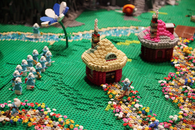 Ein Lego-Modell einer Kleinstadt mit Blumen, Spielzeugen, Häusern, Pflanzen und anderen Gegenständen, mit einem leicht unscharfen Hintergrund.