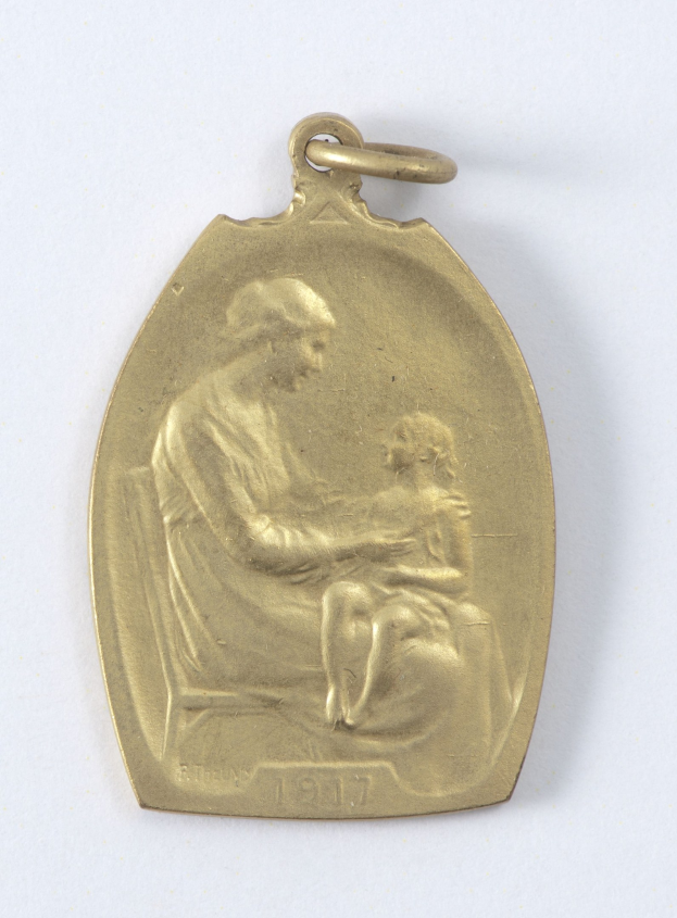Goldmedaille mit Relief einer Frau in weißem Kleid mit Haarknoten, die ein Kind hält, und der Inschrift "Mutter und Kind" in Kursivschrift.