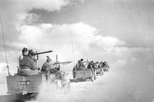 Schwarzes und weißes Bild einer Gruppe von Männern auf einem Jeep, jeder hält eine Waffe in der Hand.