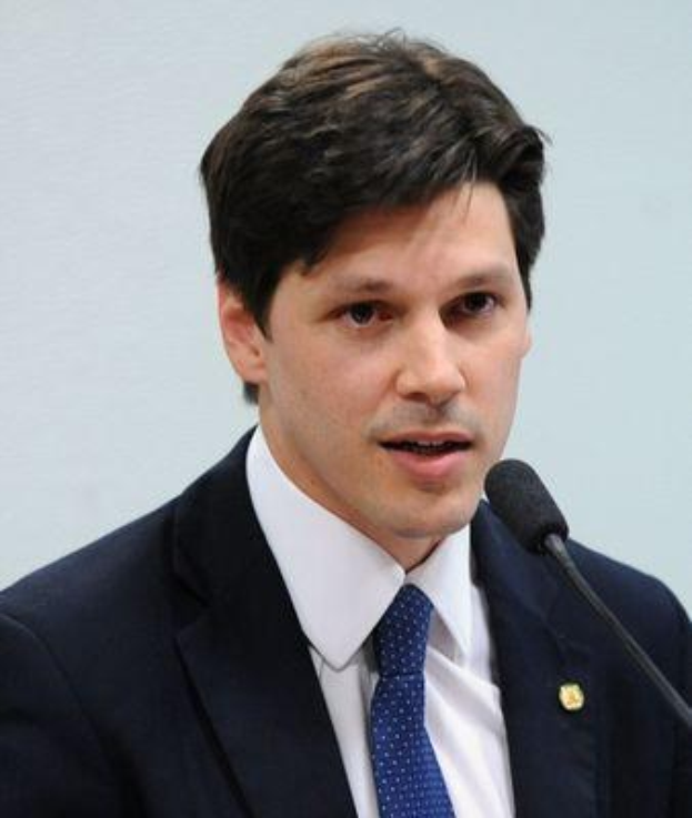 Ein Mann im Anzug spricht in ein Mikrofon, wahrscheinlich um die Genehmigung eines Gesetzes durch die Regierung zu kritisieren.