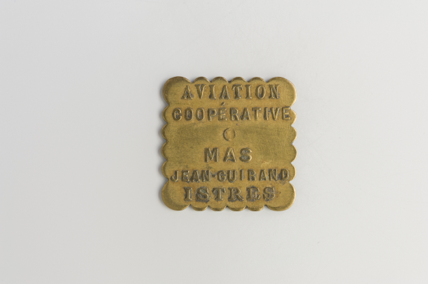 Eine Messingtafel mit der Aufschrift "Luftfahrtkooperative" vor einem weißen Hintergrund.