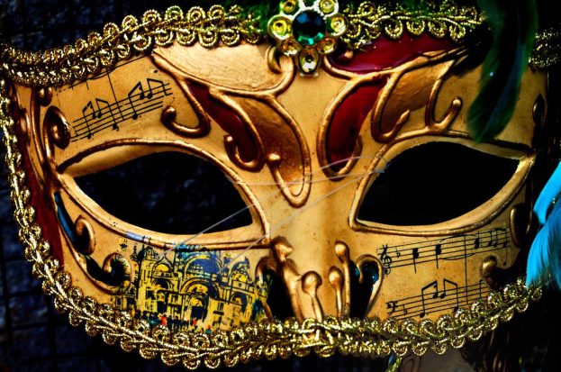 Ein Nahaufnahme eines Karnevalsmasken mit Musiknoten, detaillierten Designs und Federn, mit einem unscharfen Hintergrund.