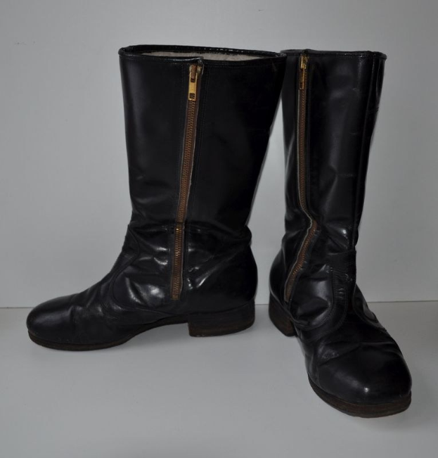 Schwarze Lederstiefel mit silbernen Reißverschlüssen auf einem weißen Hintergrund, mit einem glänzenden Finish und einem schlanken Design.
