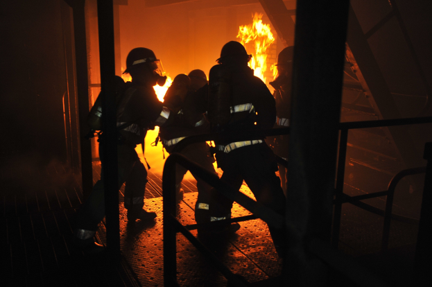 Feuerwehrleute in Schutzausrüstung vor einem brennenden Gebäude