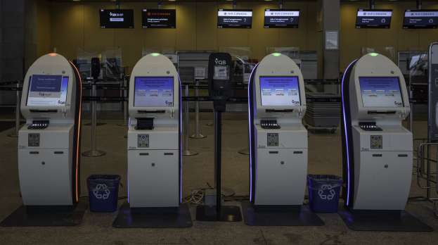 Eine Reihe von Geldautomaten auf einem gefliesten Boden mit Mülltonnen, Pfosten, Schildern mit Text und Lichtern im Hintergrund.