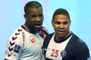 Zwei Männer in weißen und blauen Fußballtrikots stehen auf einem Feld und richten ihre Arme zum Sieg gegen einen hellblauen Hintergrund.