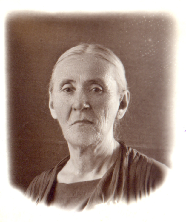 Eine alte Frau mit ernstem Gesichtsausdruck, die ein weißes Kleid trägt und ihr Haar zurückgekämmt hat, die nachdenklich und nachdenklich aussieht.