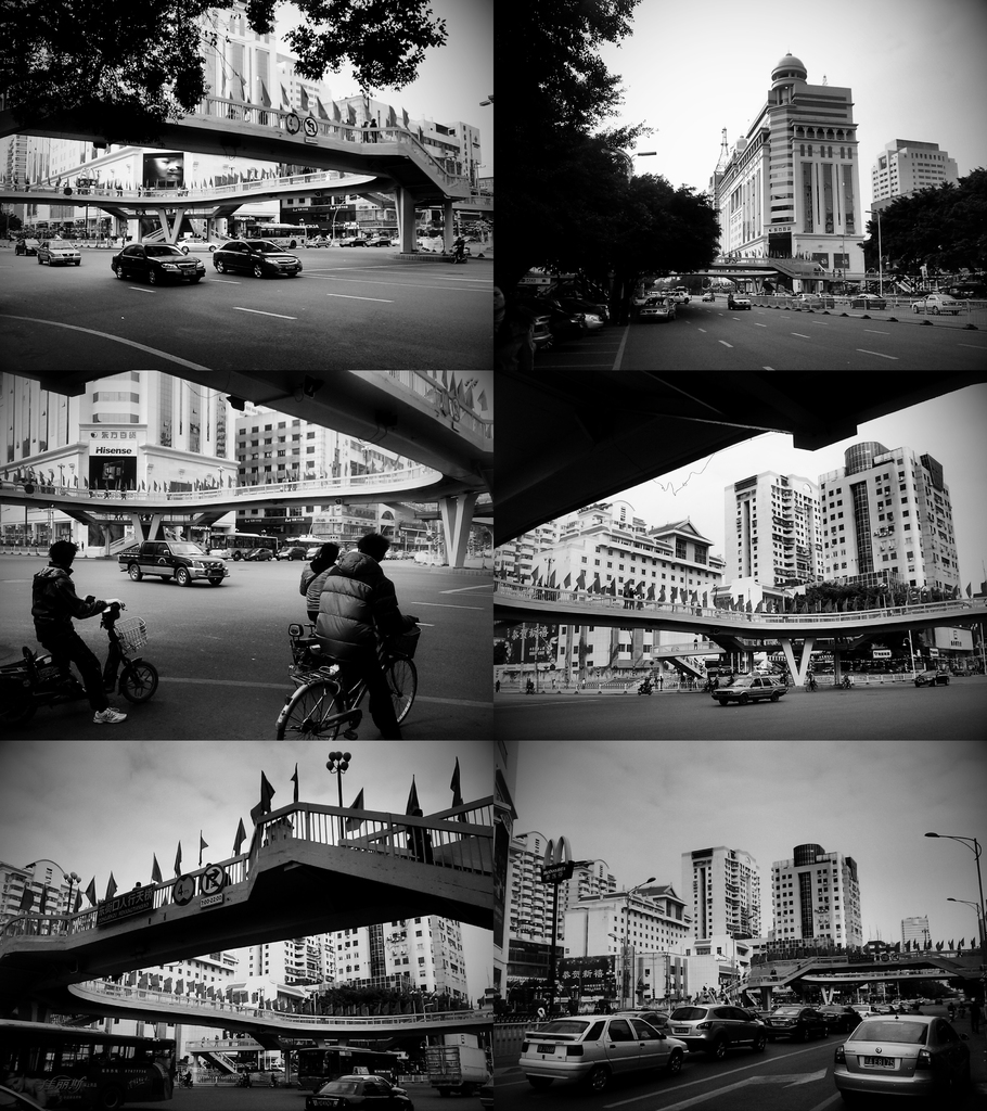 Autos und Fahrräder unter einer Brücke, mit einigen Fahrzeugen vor einem Gebäude.